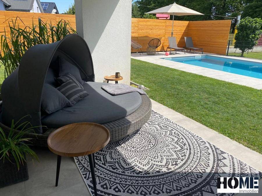 Entspannungsbereich auf der Terrasse mit Tagesbett und direktem Blick auf den Pool.