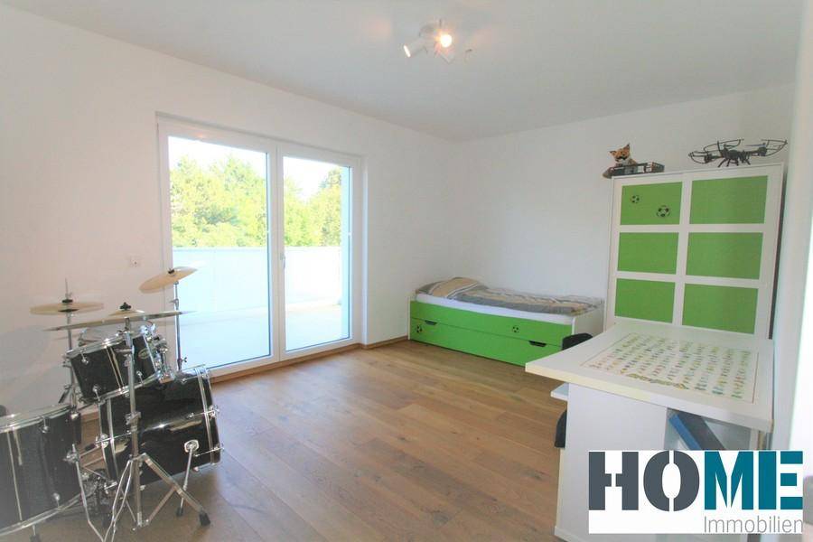 Helles Kinderzimmer mit Holzboden, Schlagzeug und Zugang zu einem großen Balkon oder einer Terrasse.