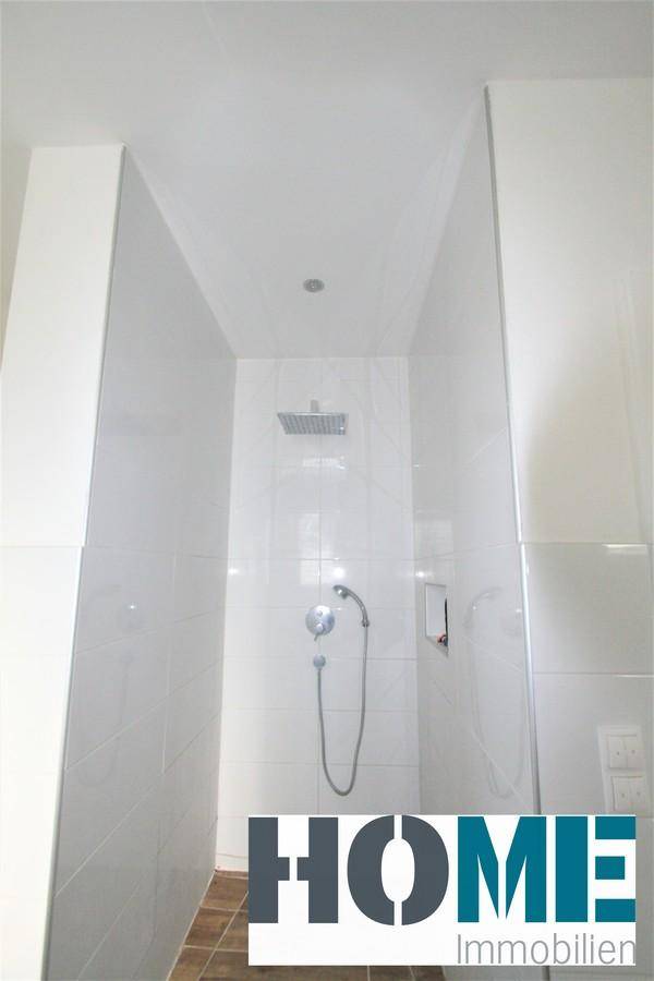 Geräumige begehbare Dusche mit Regenduschkopf und Handbrause, modern gefliest.