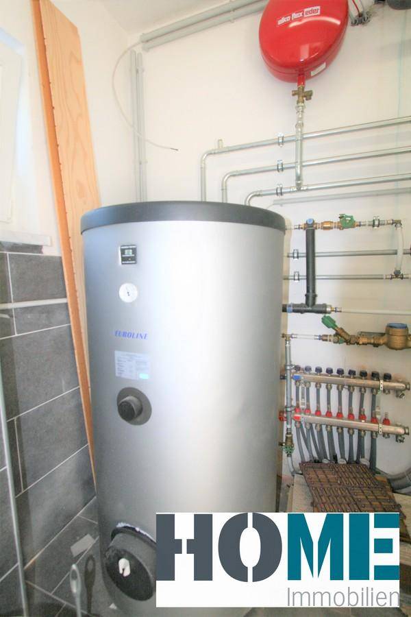 Hauswirtschaftsraum mit Warmwasserspeicher und komplexen Rohrinstallationen, funktional eingerichtet.
