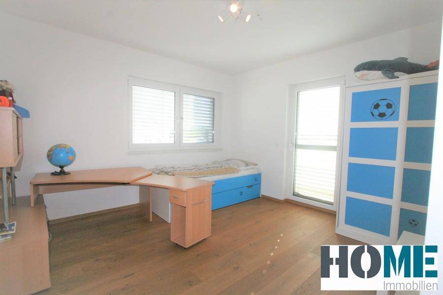 Freundliches Kinderzimmer mit Holzboden, Schreibtisch und einem blauen Schrank mit Fußballmotiv.