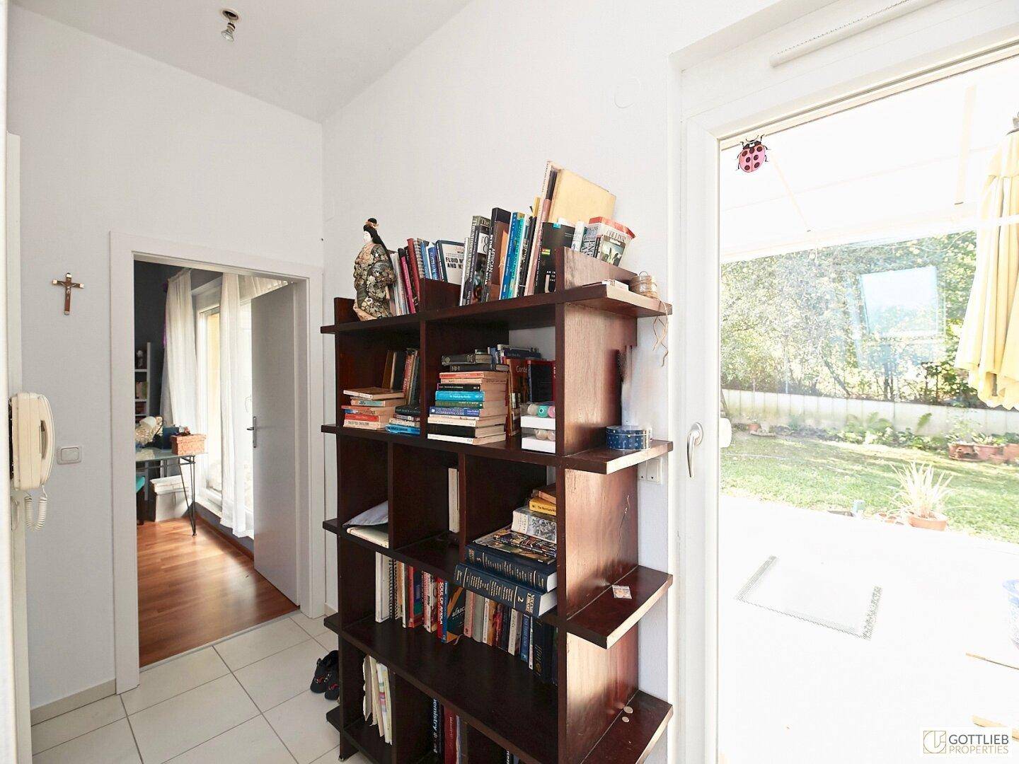 Heller Flur mit Bücherregal und direktem Zugang zur Terrasse und zum Garten.