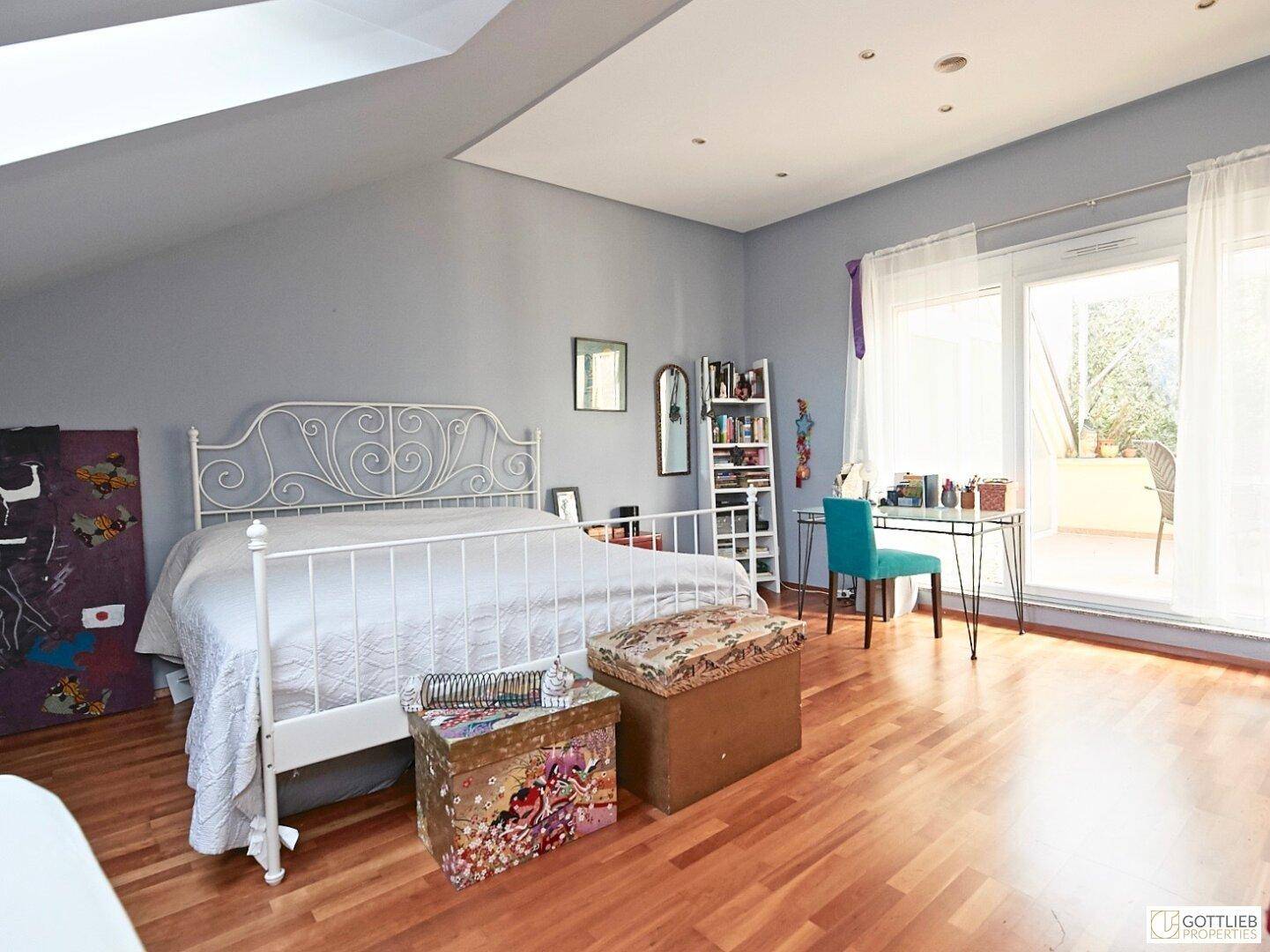 Geräumiges Schlafzimmer im Dachgeschoss mit Holzboden und Zugang zu einem Balkon.