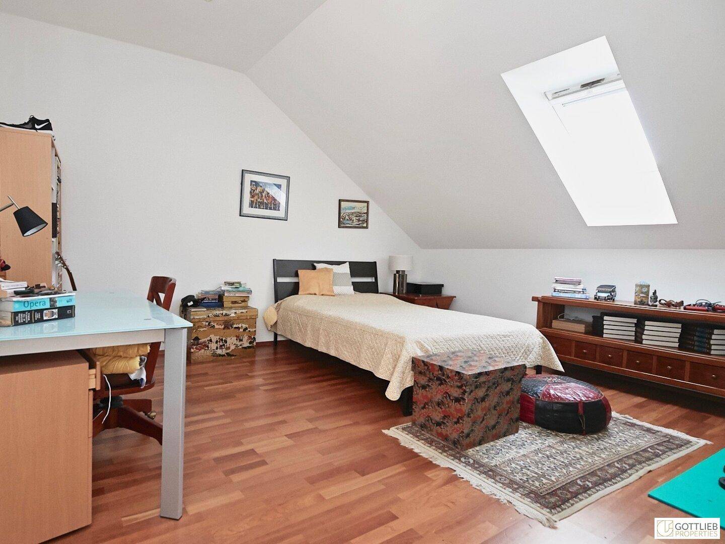 Helles Schlafzimmer im Dachgeschoss mit Holzboden, Dachfenster und viel Stauraum.