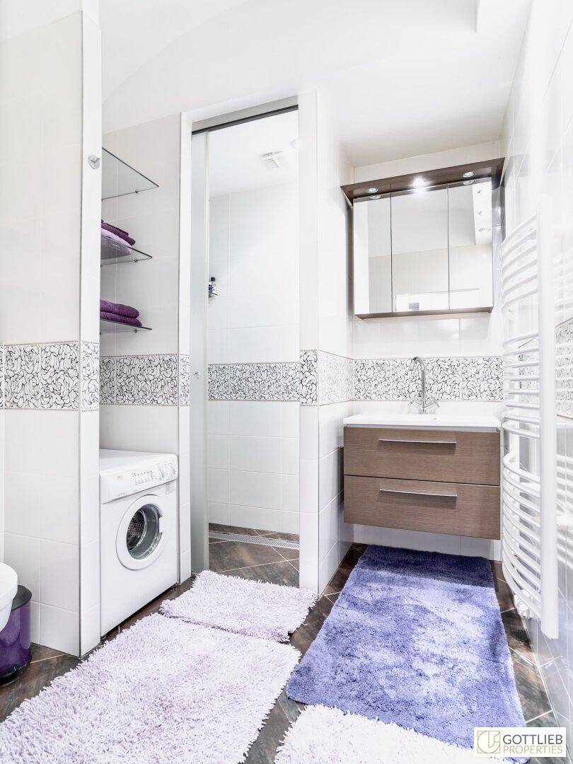 Modernes Badezimmer mit Waschbecken, Spiegelschrank und integrierter Waschmaschine.