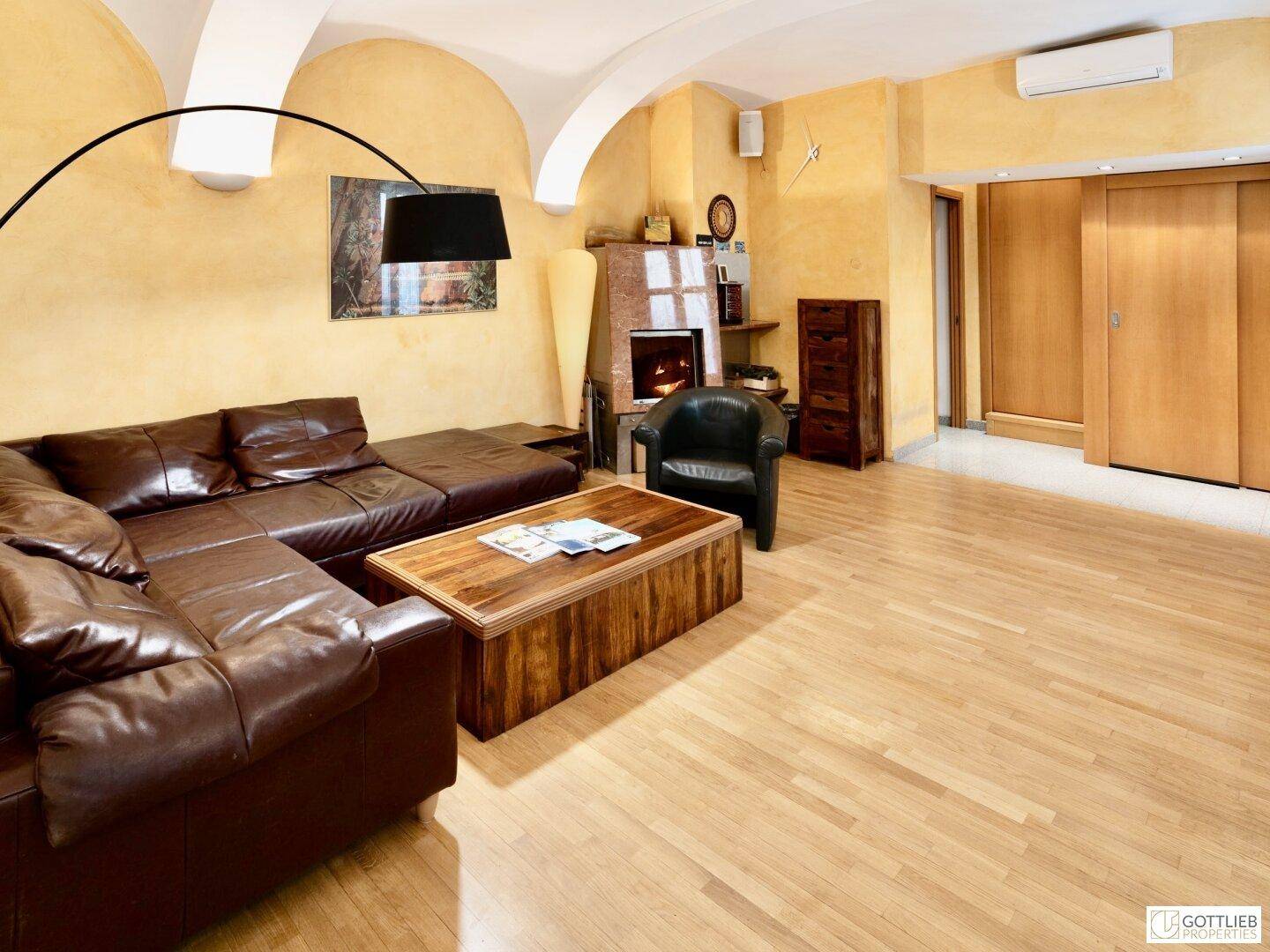 Heller Wohnbereich mit Ledersofa, Kamin, Klimaanlage und eleganten Gewölbedecken.