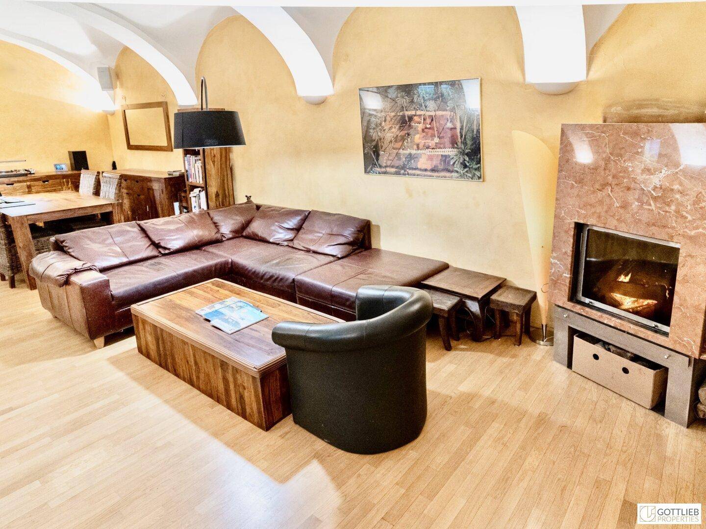 Gemütliches Wohnzimmer mit großer Ledercouch, Holztisch und modernem Kamin.