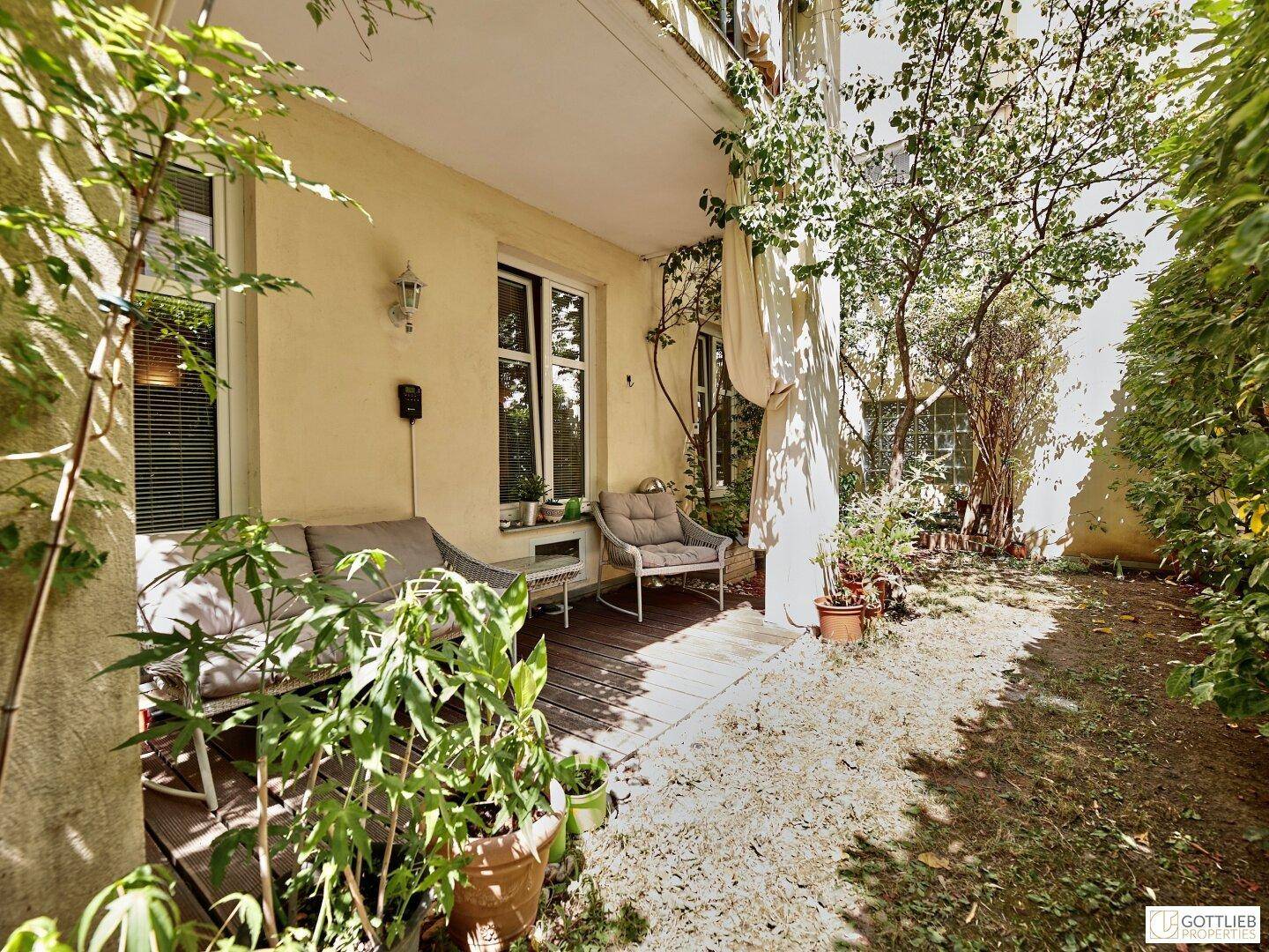 Gemütlicher Terrassenbereich mit Holzdeck, Gartenmöbeln und umgebender Bepflanzung.