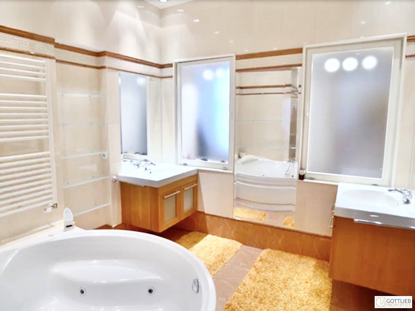 Luxuriöses Badezimmer mit Eckbadewanne, zwei Waschbecken und beheiztem Handtuchhalter.