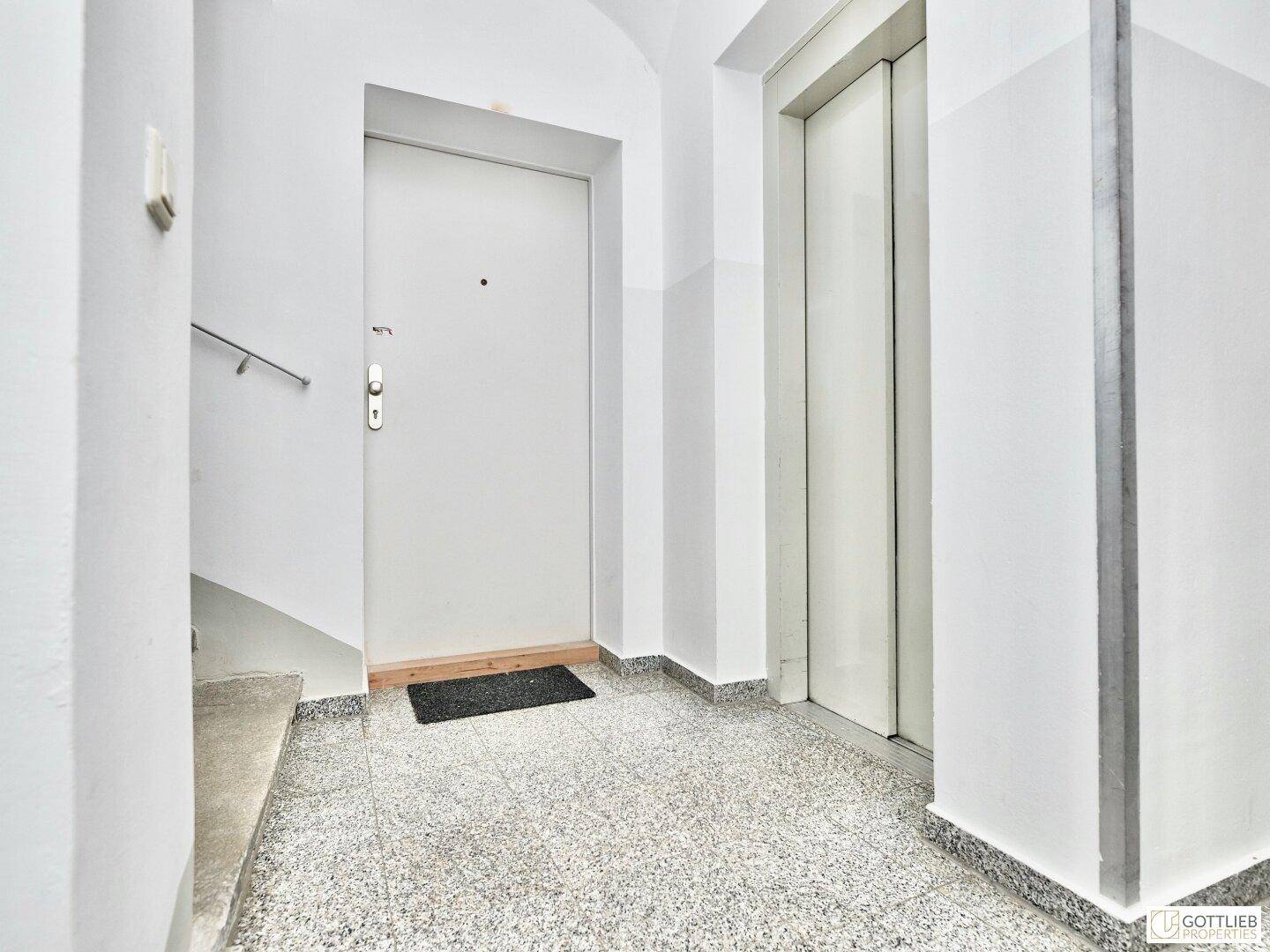 Heller Flur mit Aufzug und Zugang zu einer Wohnung.