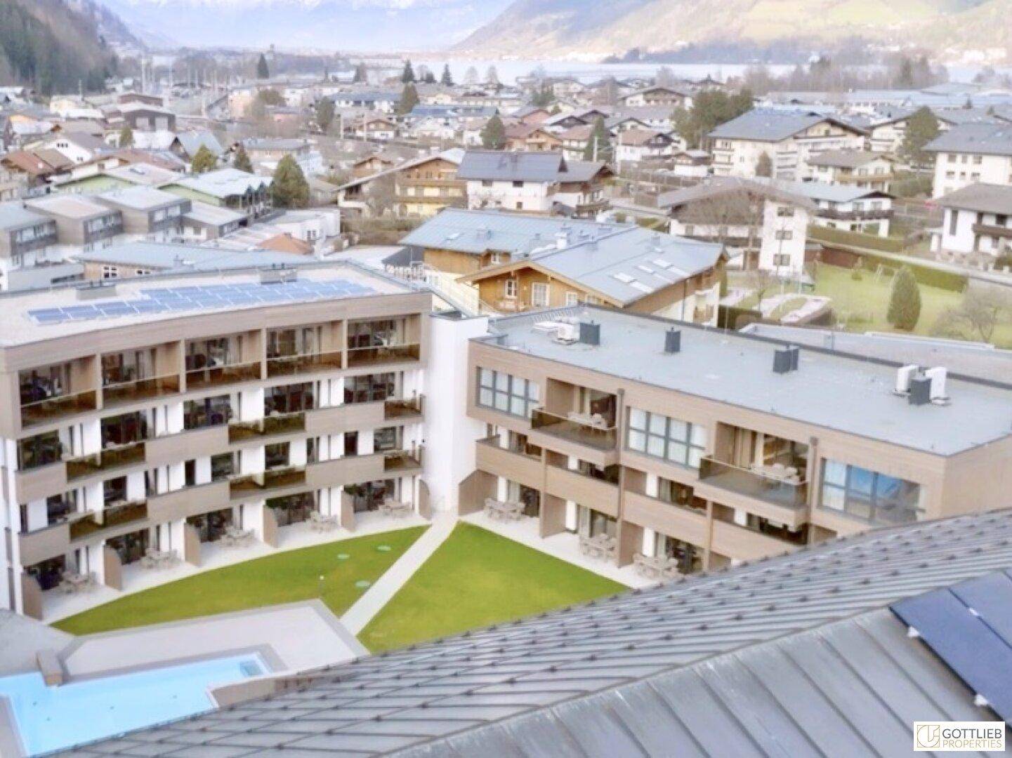 Luftaufnahme einer modernen Wohnanlage mit Pool und Blick auf die umliegende Stadt und Berge.
