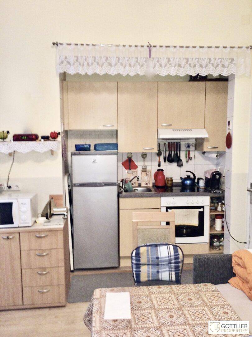 Kleine Küche mit Einbauschränken, Kühlschrank und Herd, angrenzend an einen Essbereich.