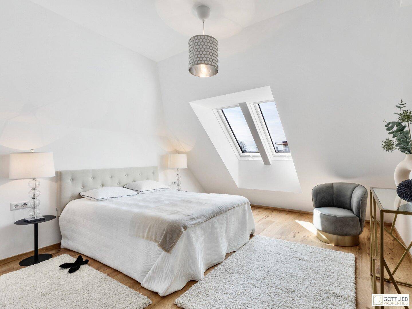 Helles Schlafzimmer im Dachgeschoss mit Doppelbett, Dachfenstern und Holzboden.