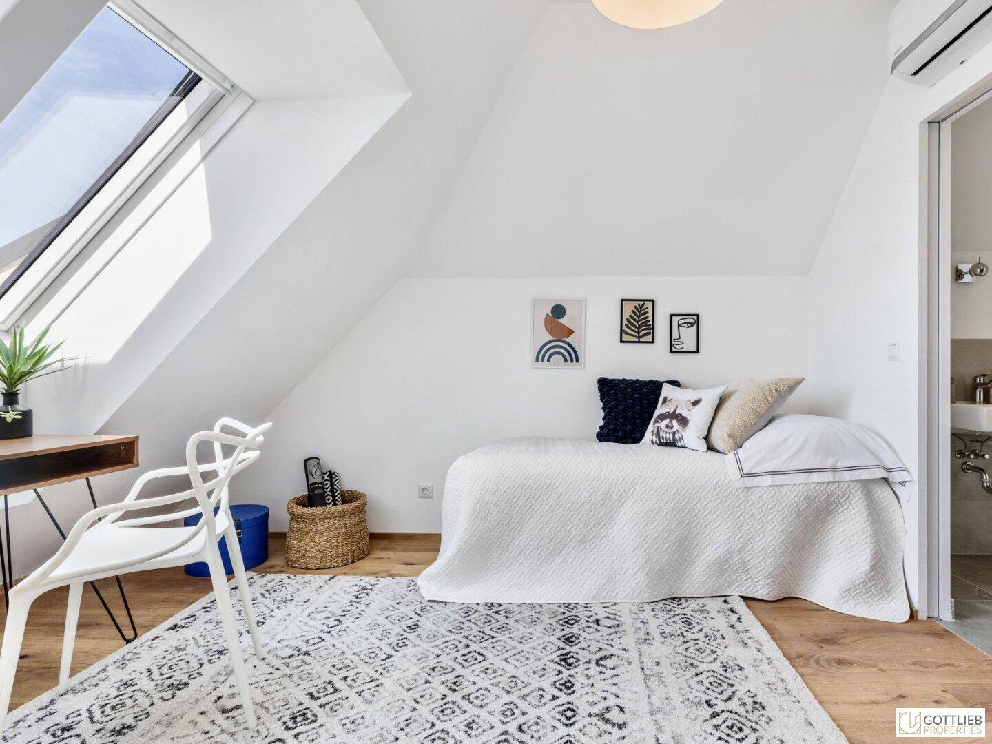 Kinderzimmer im Dachgeschoss mit Einzelbett, Schreibtisch, Dachfenstern und Holzboden.