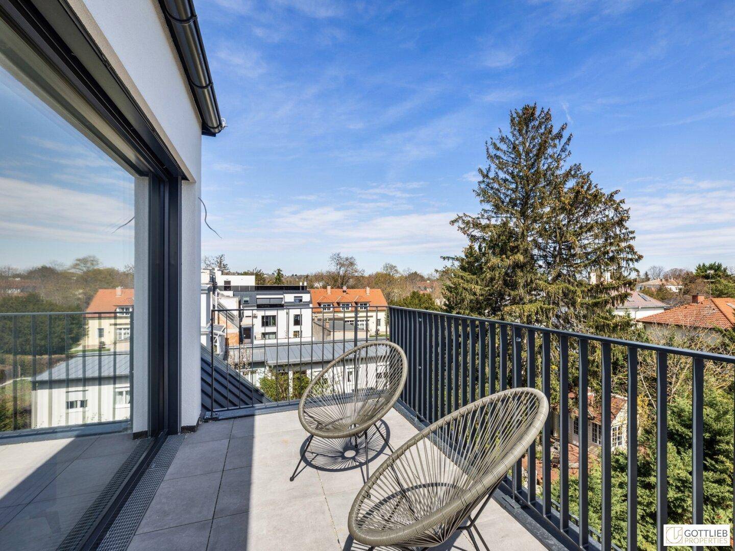 Balkon mit Sitzgelegenheiten und Blick ins Grüne sowie auf die umliegenden Gebäude.