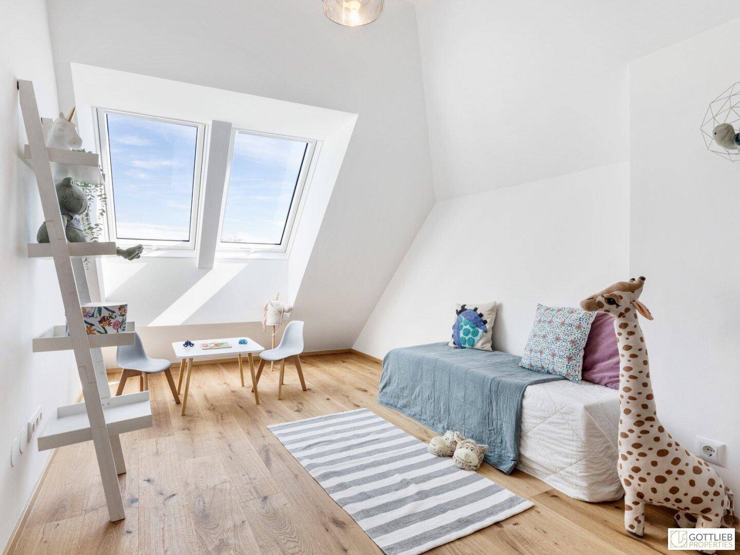 Helles Kinderzimmer im Dachgeschoss mit Bett, Spielbereich, Dachfenstern und Holzboden.