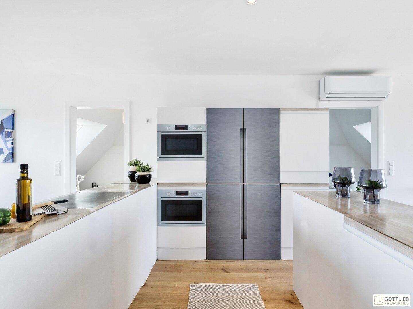 Detailansicht der modernen Küche mit integriertem Kühlschrank und Backöfen.