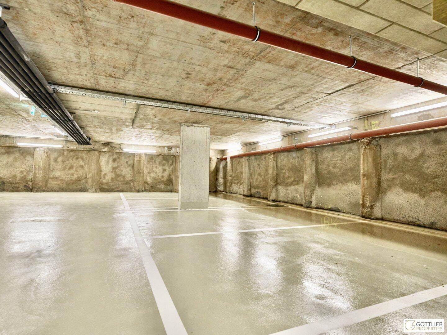 Tiefgarage mit markierten Stellplätzen, Betonwänden und Deckenkonstruktion.