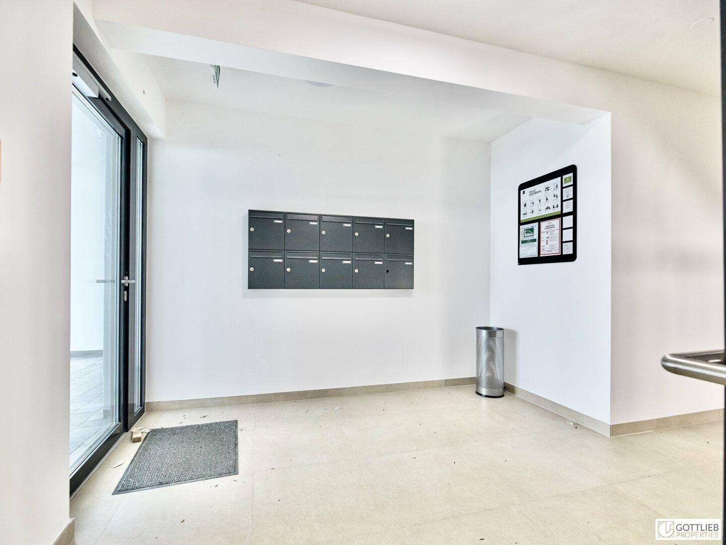 Heller Eingangsbereich mit Briefkästen und Zugang zum Außenbereich.