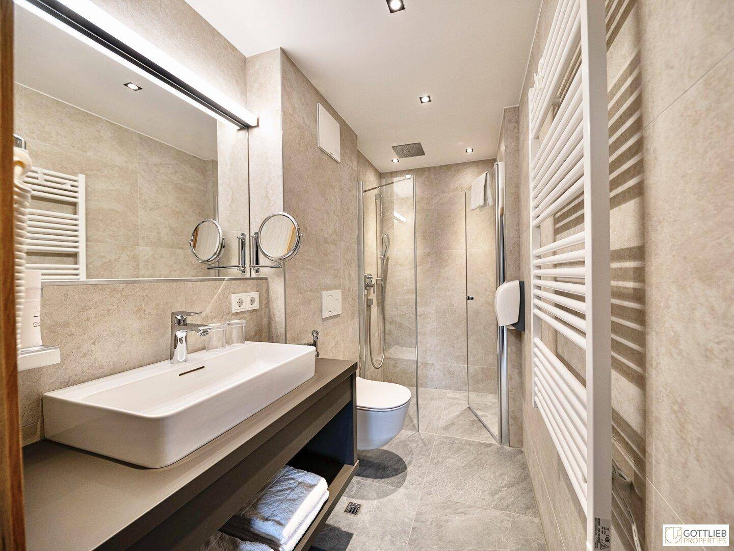 Modernes Badezimmer mit Dusche, Waschbecken und beheiztem Handtuchhalter im Dachgeschoss.
