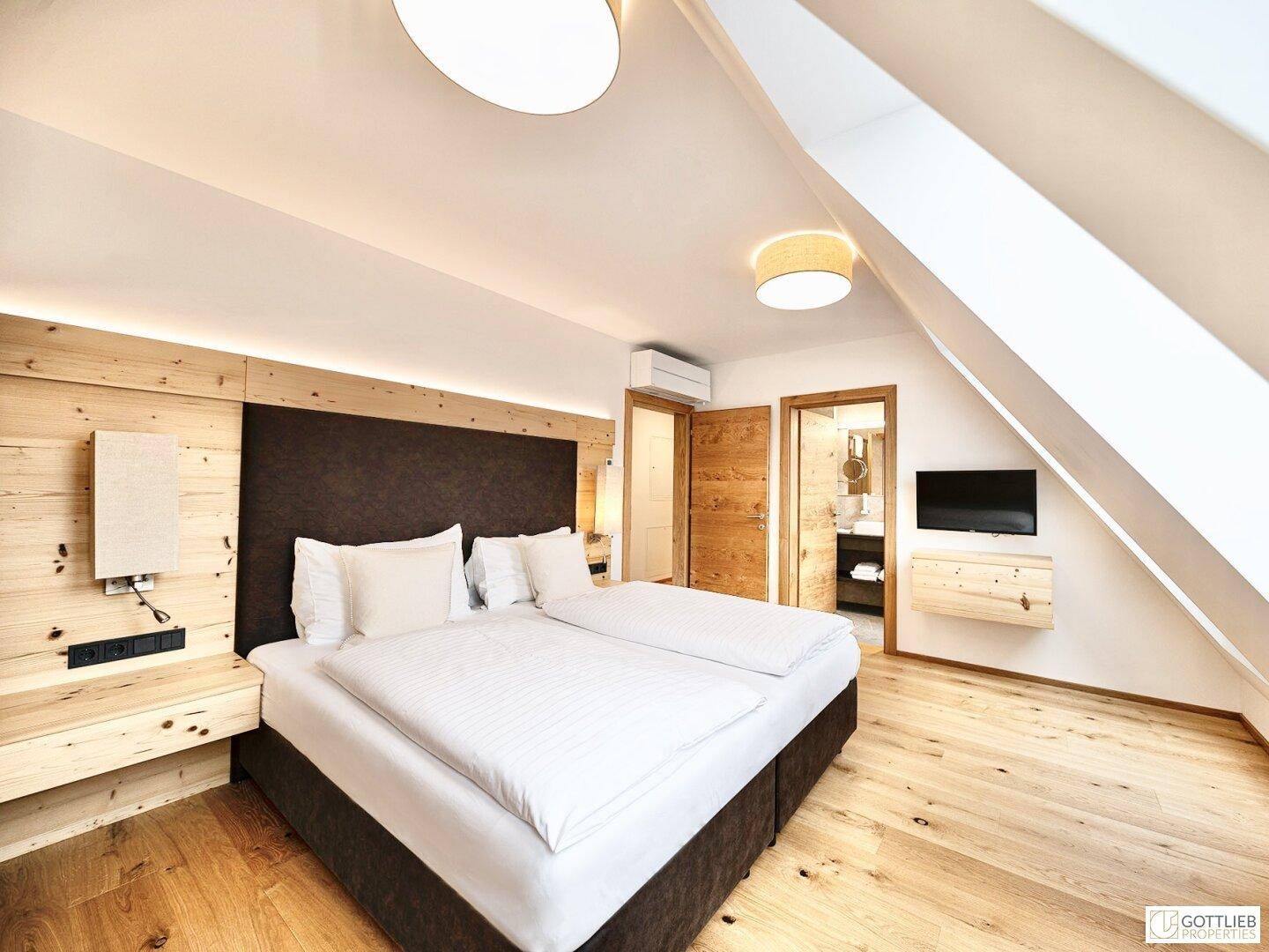 Gemütliches Schlafzimmer im Dachgeschoss mit Holzboden, Doppelbett und Dachfenstern.