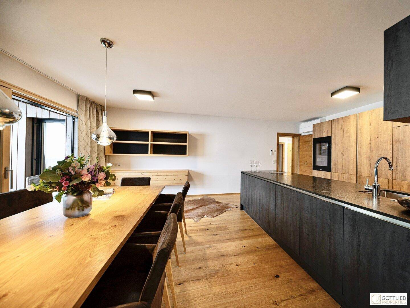 Essbereich mit Holztisch und moderner Küche, die sich in den offenen Wohnraum einfügt.