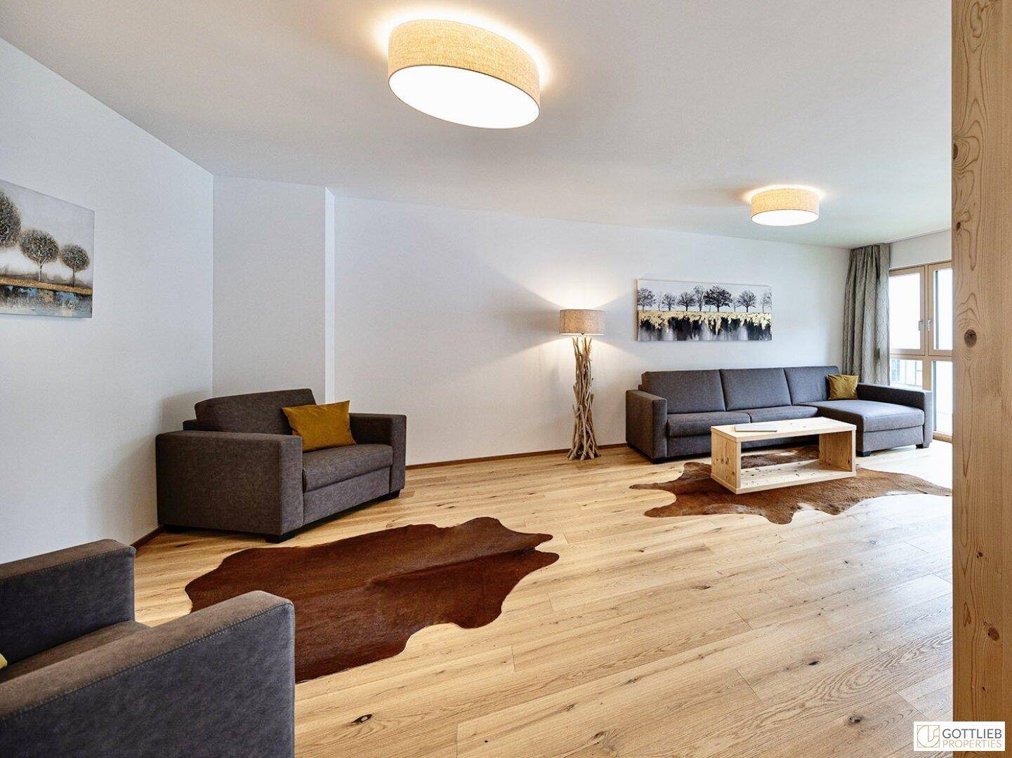 Geräumiges Wohnzimmer mit Holzboden, zwei Sofas und stilvoller Beleuchtung.