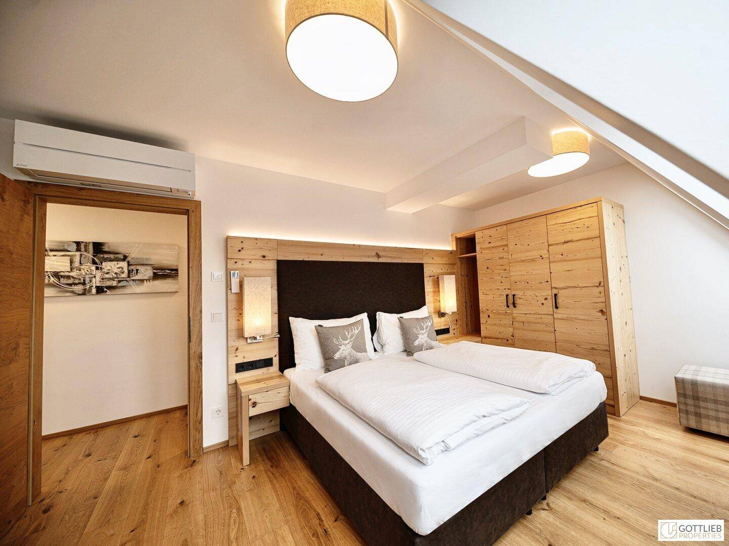 Gemütliches Schlafzimmer im Dachgeschoss mit Holzboden, Doppelbett und Holzschrank.