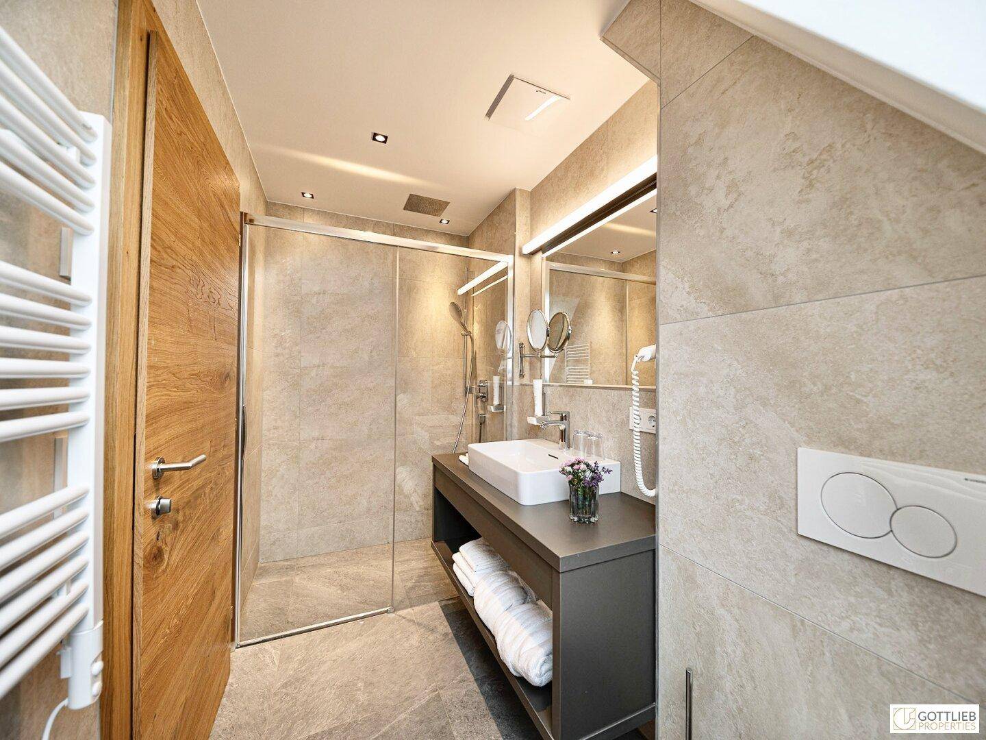 Modernes Badezimmer mit Dusche, Waschbecken und beheiztem Handtuchhalter im Dachgeschoss.