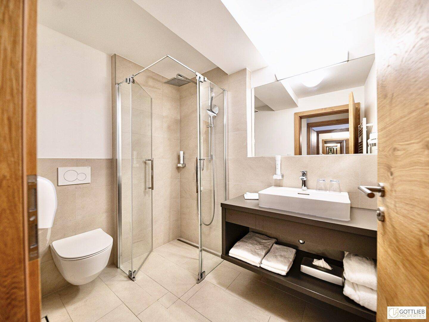 Modernes Badezimmer mit ebenerdiger Dusche, Wand-WC und elegantem Waschtisch mit Stauraum.