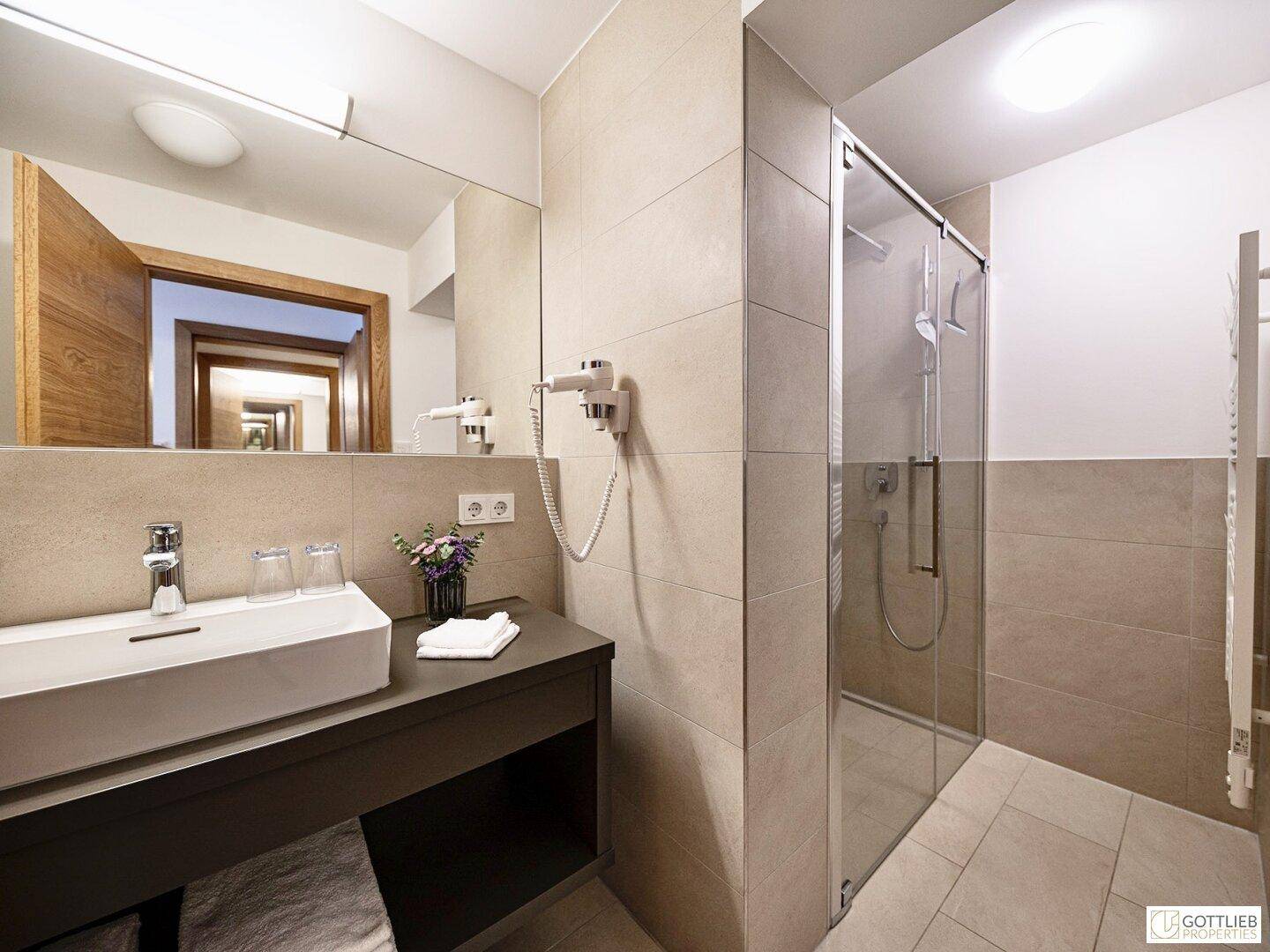 Helles Badezimmer mit großer Dusche, modernem Waschtisch und Spiegel, funktional und stilvoll.