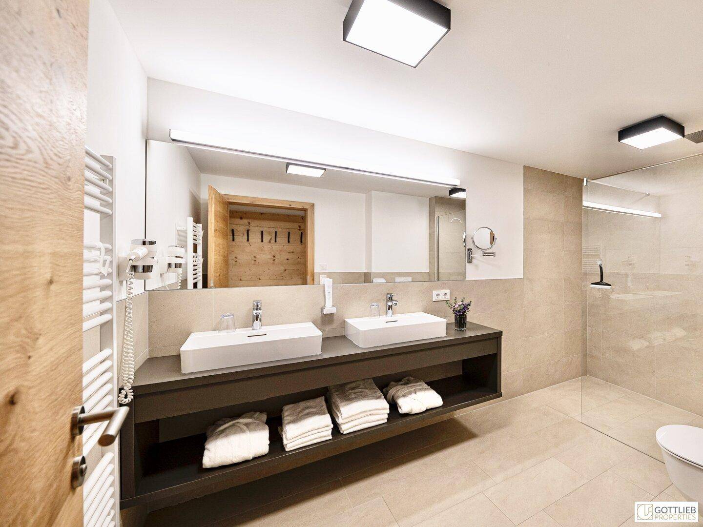 Modernes Badezimmer mit Doppelwaschbecken, großer Spiegelfläche und ebenerdiger Dusche.
