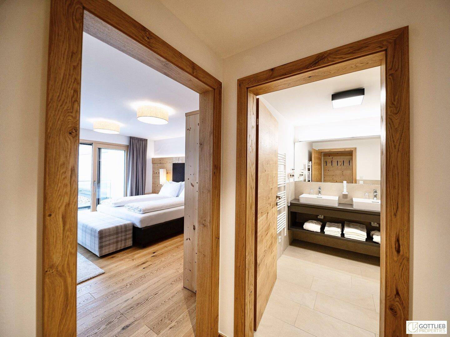 Heller Flur mit Holztürrahmen, der zu einem Schlafzimmer und einem modernen Badezimmer führt.