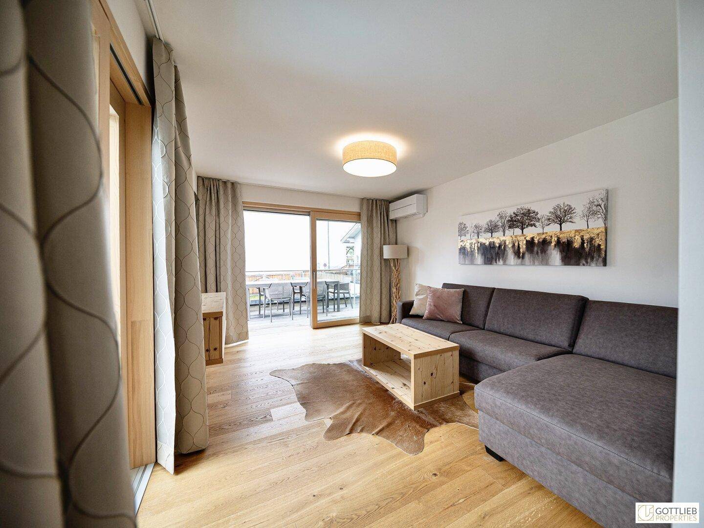 Helles Wohnzimmer mit Zugang zu einem Balkon oder einer Terrasse durch große Schiebetüren.