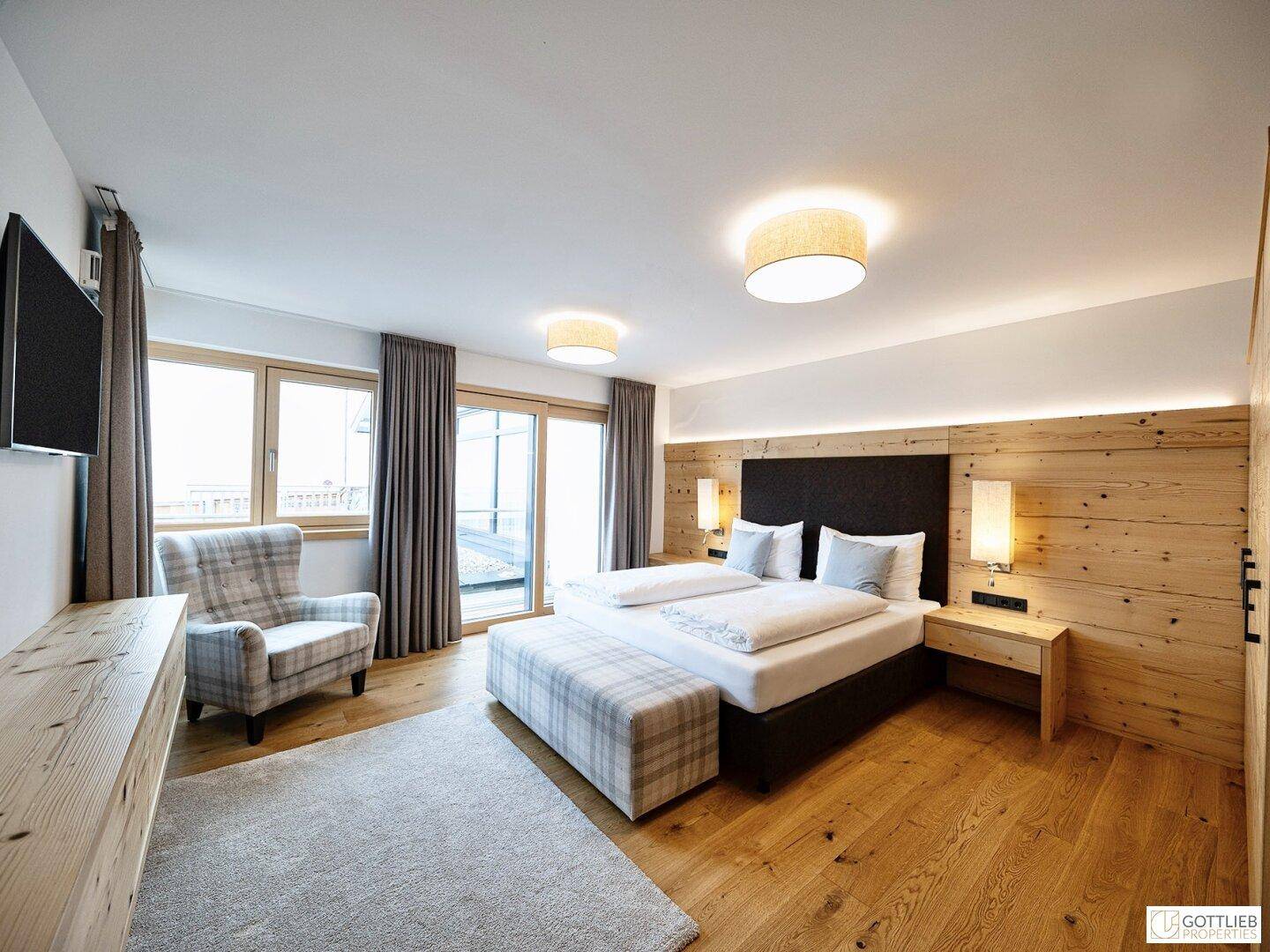 Gemütliches Schlafzimmer mit Doppelbett, Holzwand und Zugang zu einem Außenbereich, hell und einladend.