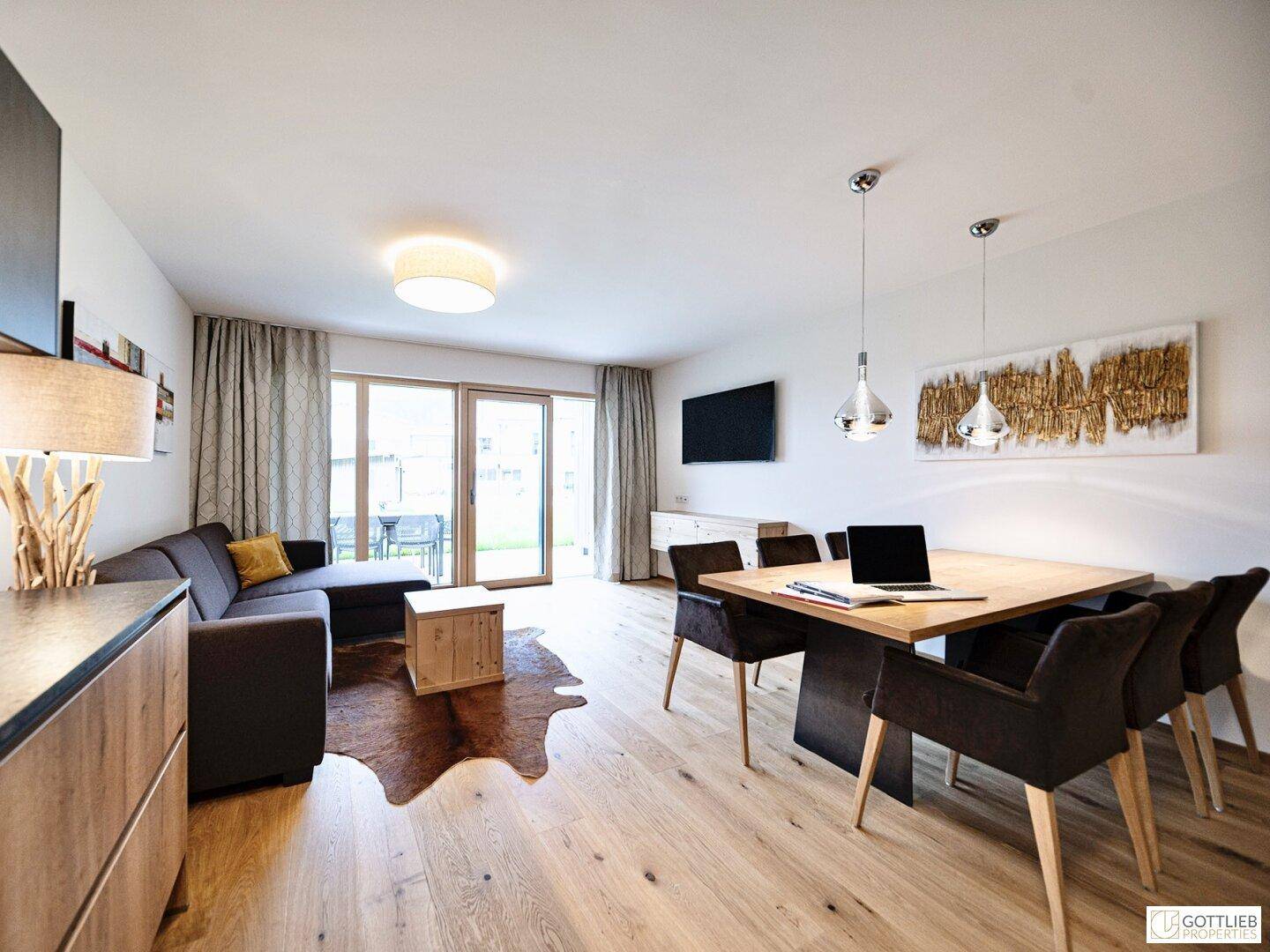 Heller Wohn- und Essbereich mit Holzboden, Sofa und Zugang zur Terrasse.