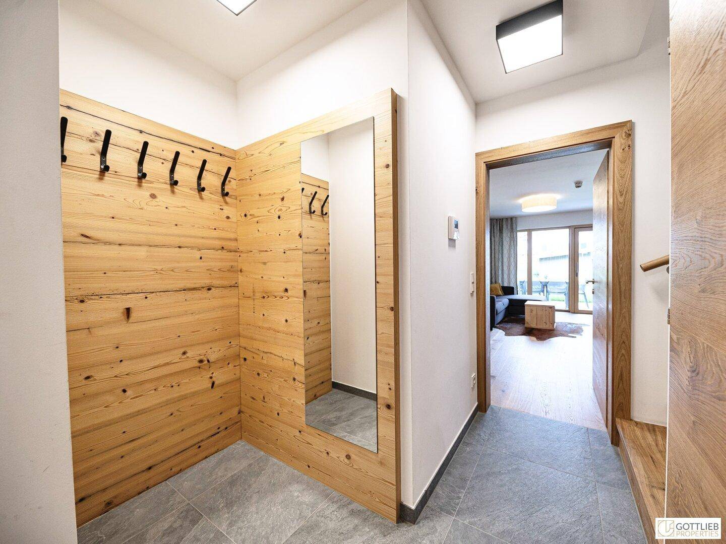 Heller Flur mit Holzwandverkleidung, Spiegel und Garderobe.