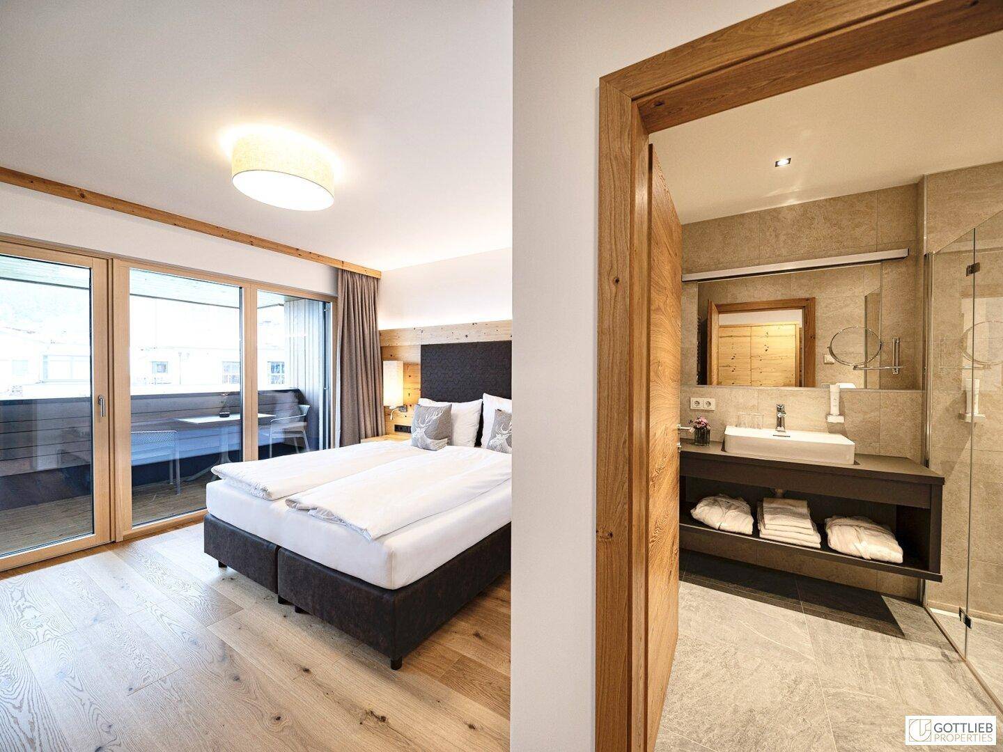Schlafzimmer mit Balkonzugang und angrenzendem modernen Badezimmer.