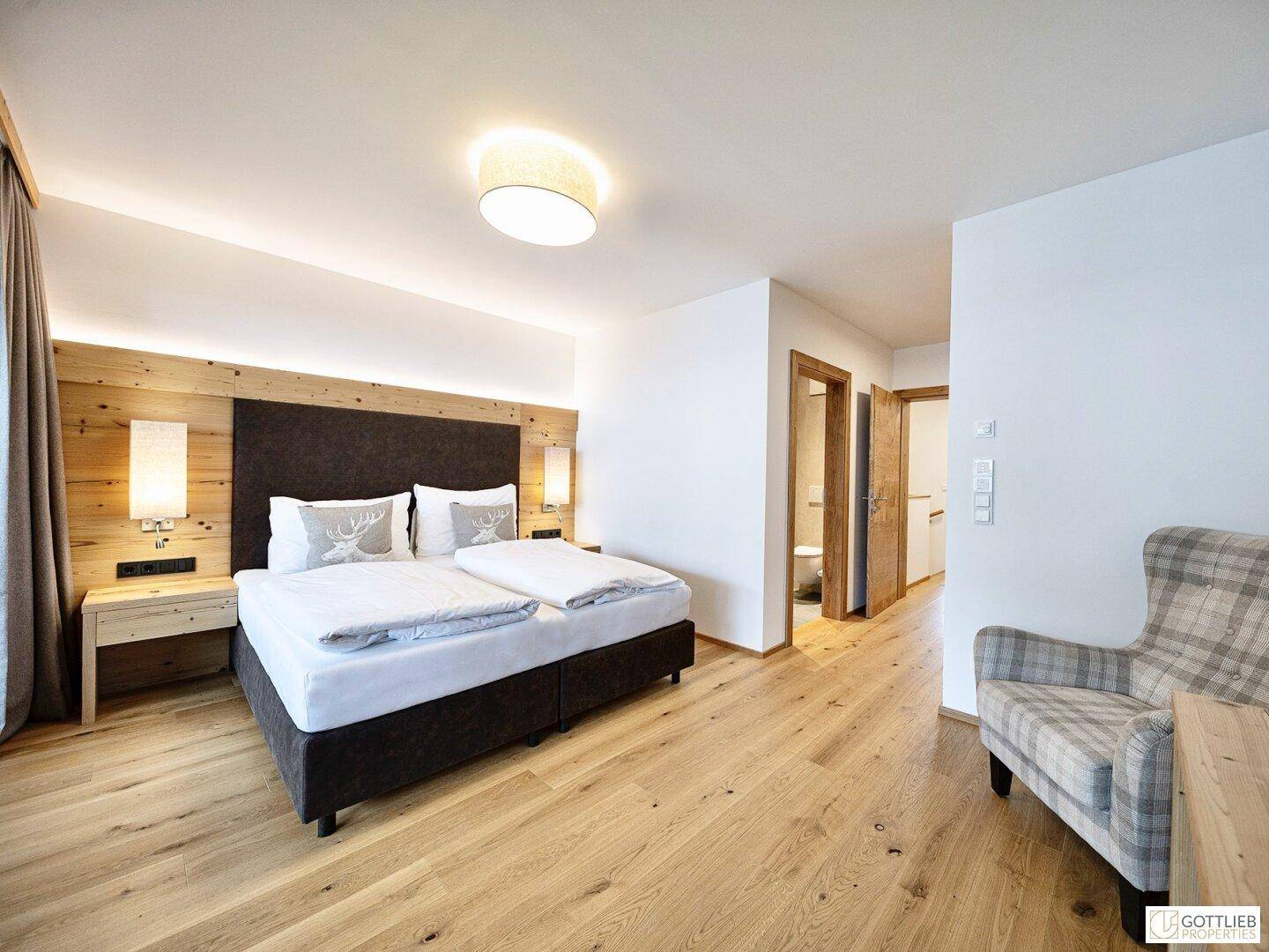 Geräumiges Schlafzimmer mit Holzboden, bequemen Bett und Blick auf den angrenzenden Flur.