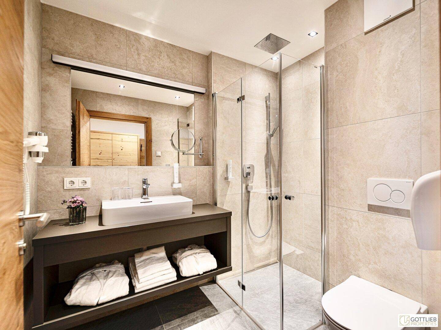Modernes Badezimmer mit begehbarer Dusche, Einzelwaschbecken und hellen Fliesen.