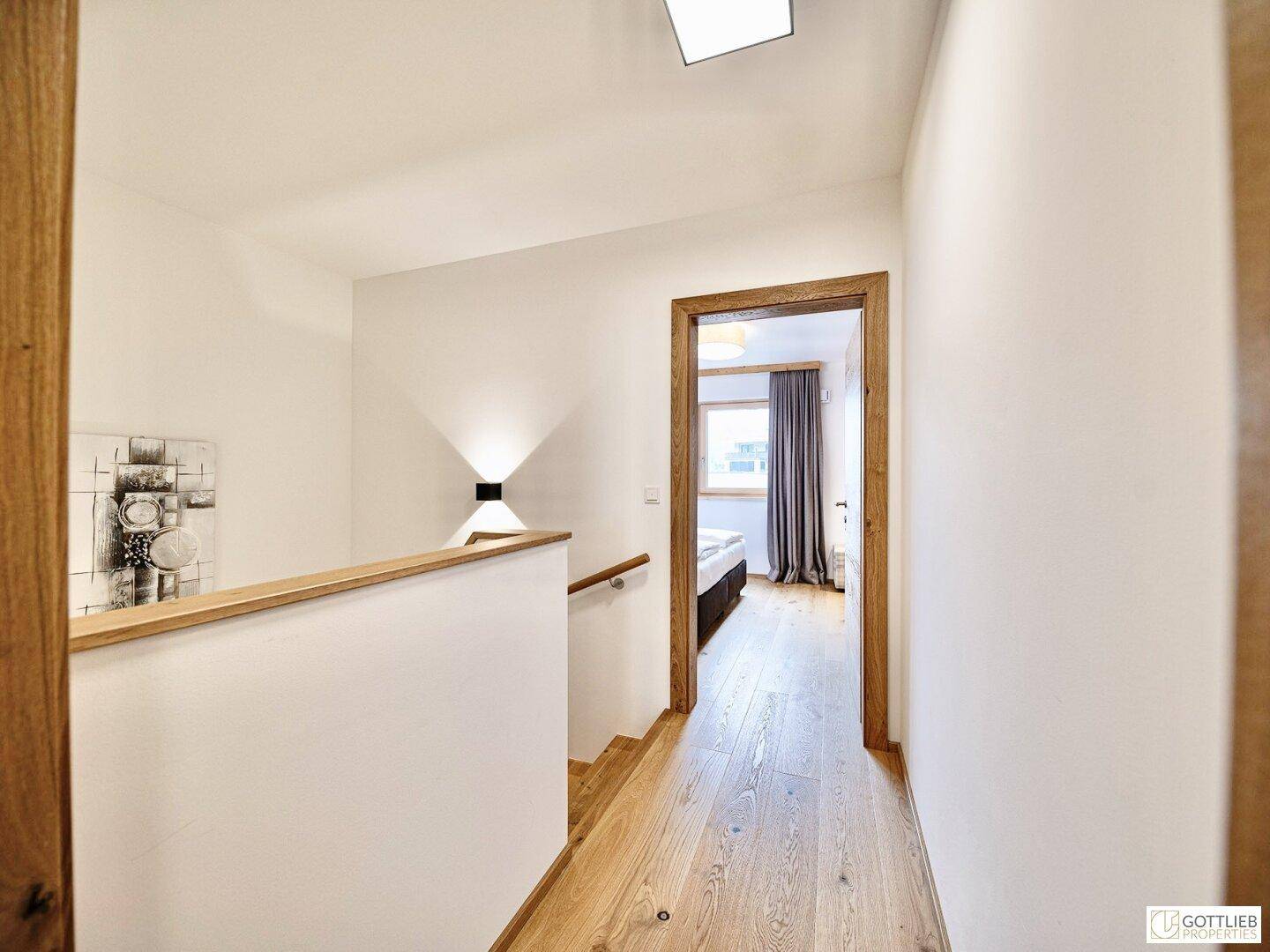 Heller Flur im Obergeschoss mit Holzboden und Blick in ein Schlafzimmer.