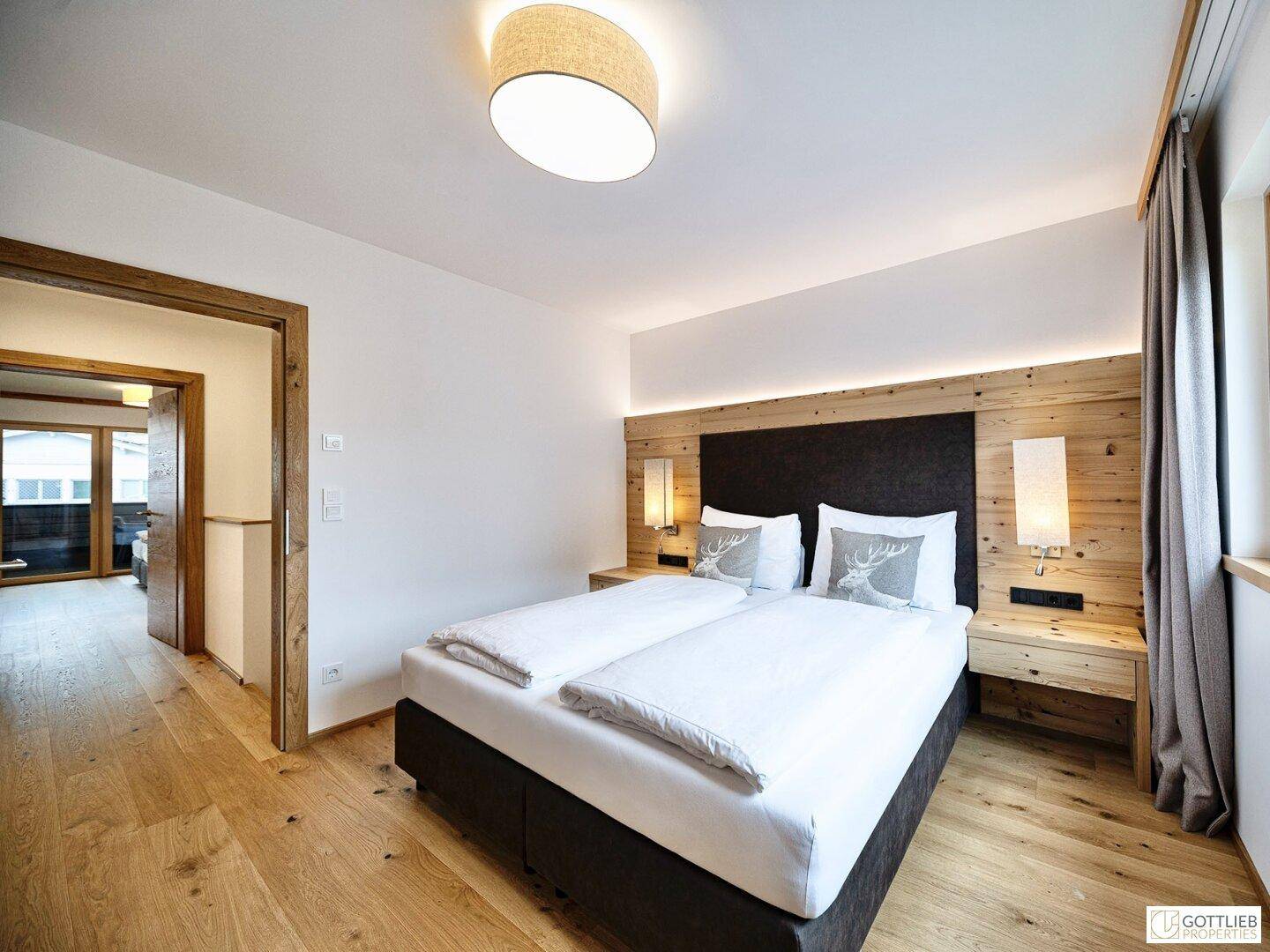 Schlafzimmer mit Holzboden und Holzwand, Blick in den Flur und zum Balkon.