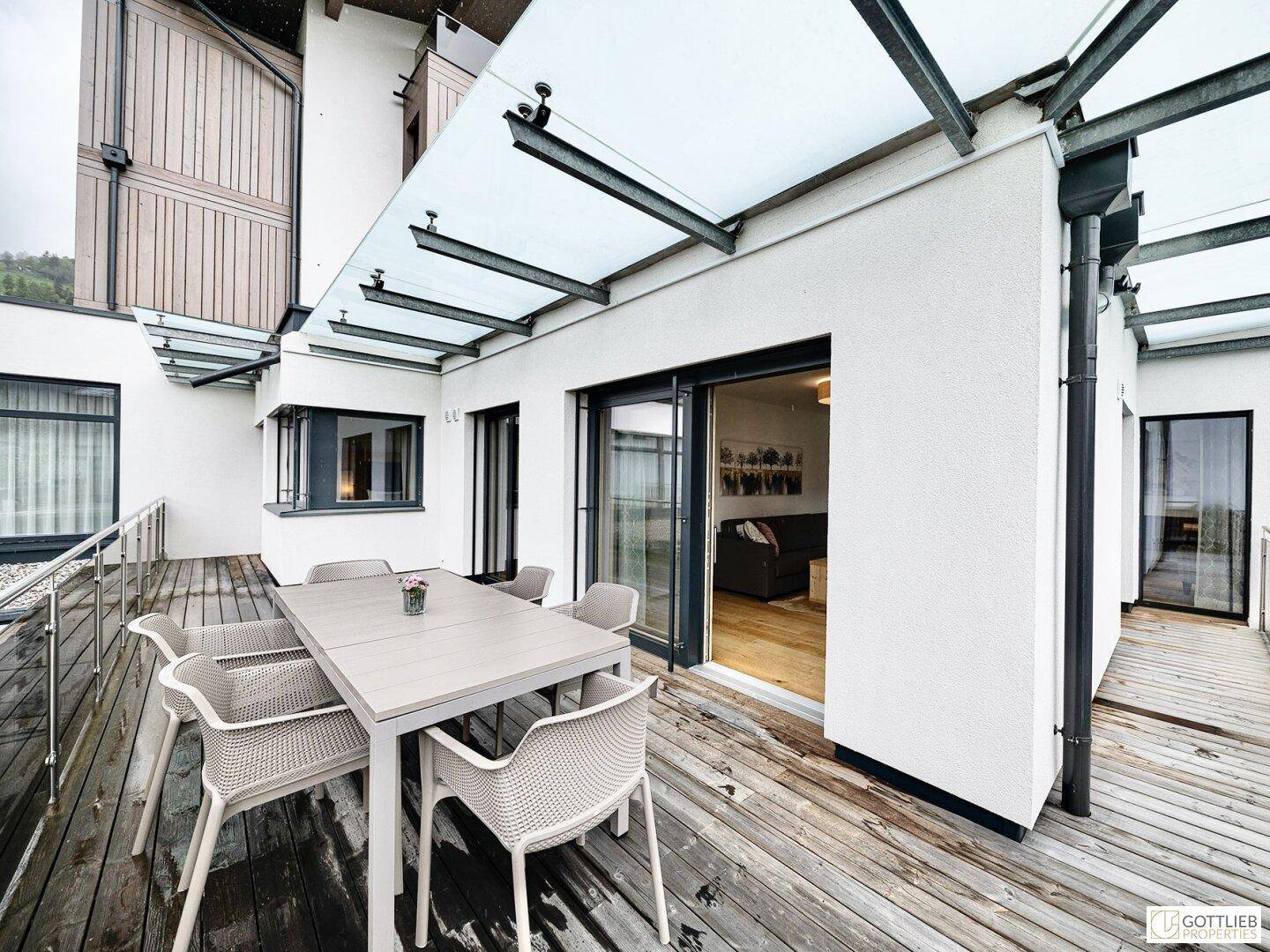 Geräumige Terrasse mit Esstisch und Stühlen, überdacht mit einem modernen Glasdach, ideal für Mahlzeiten im Freien.