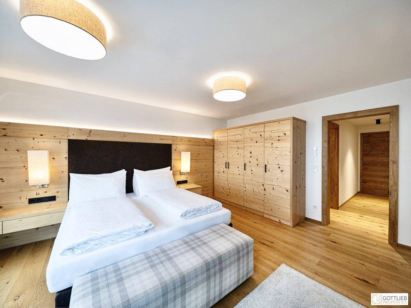 Geräumiges Schlafzimmer mit Doppelbett, Holzwand und großem Holzschrank, mit Holzboden.
