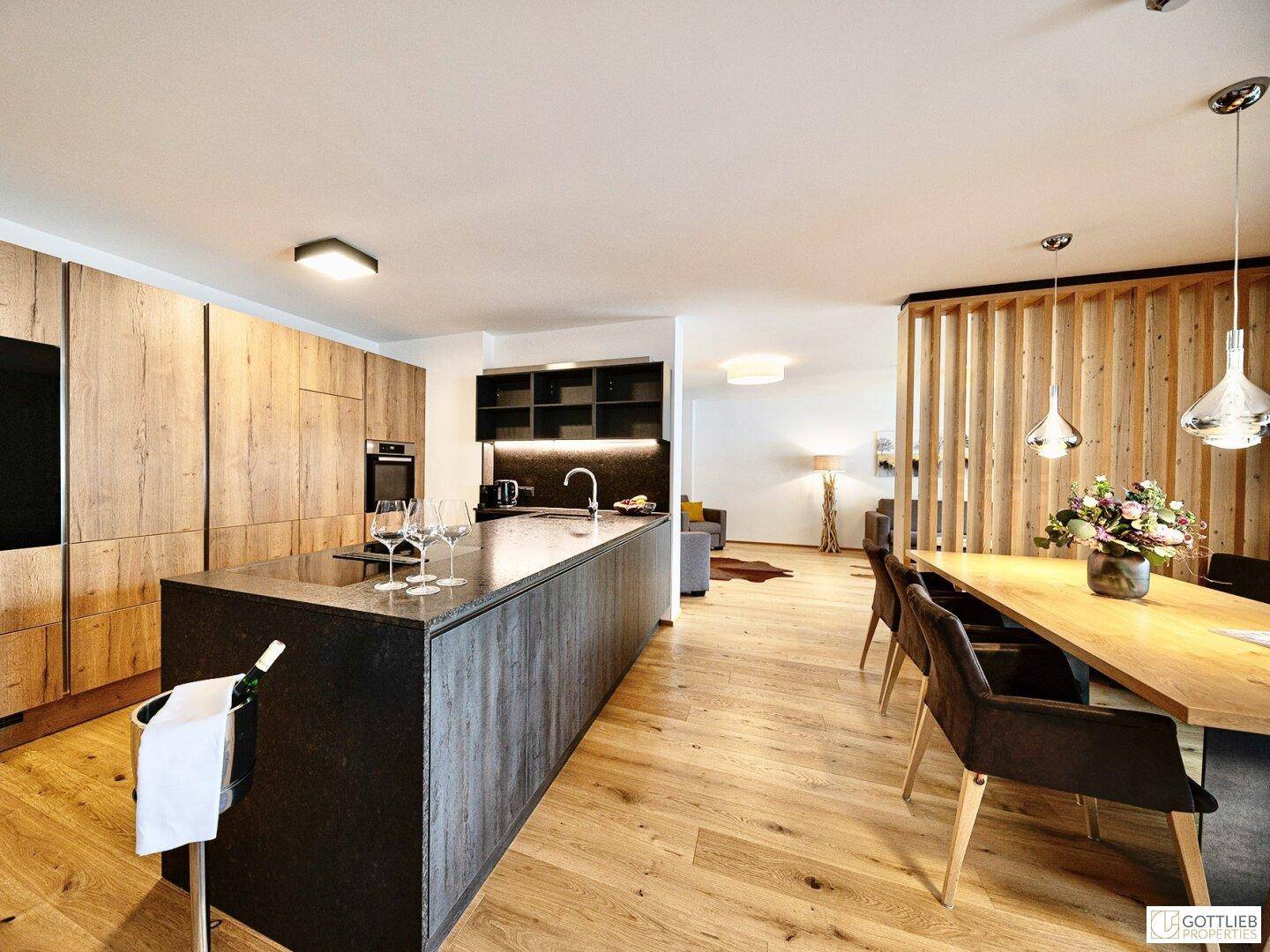 Elegante Küche mit Holzfronten, dunkler Kücheninsel und offenem Übergang zum Essbereich.