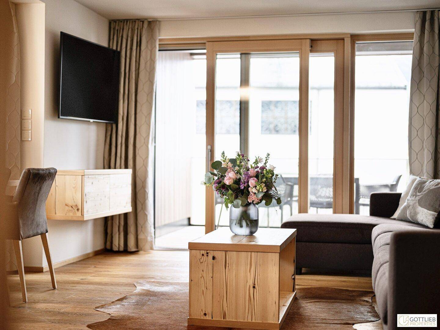 Gemütliches Wohnzimmer mit Sofa, Couchtisch und Zugang zu einem Balkon oder einer Terrasse.