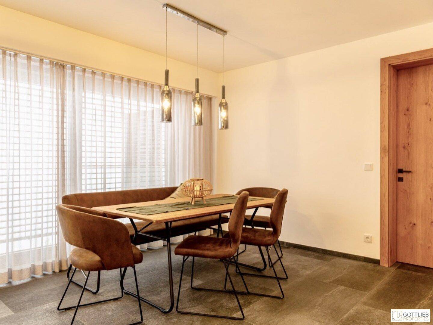 Eleganter Essbereich mit modernem Holztisch, bequemen Stühlen und großen Fenstern.