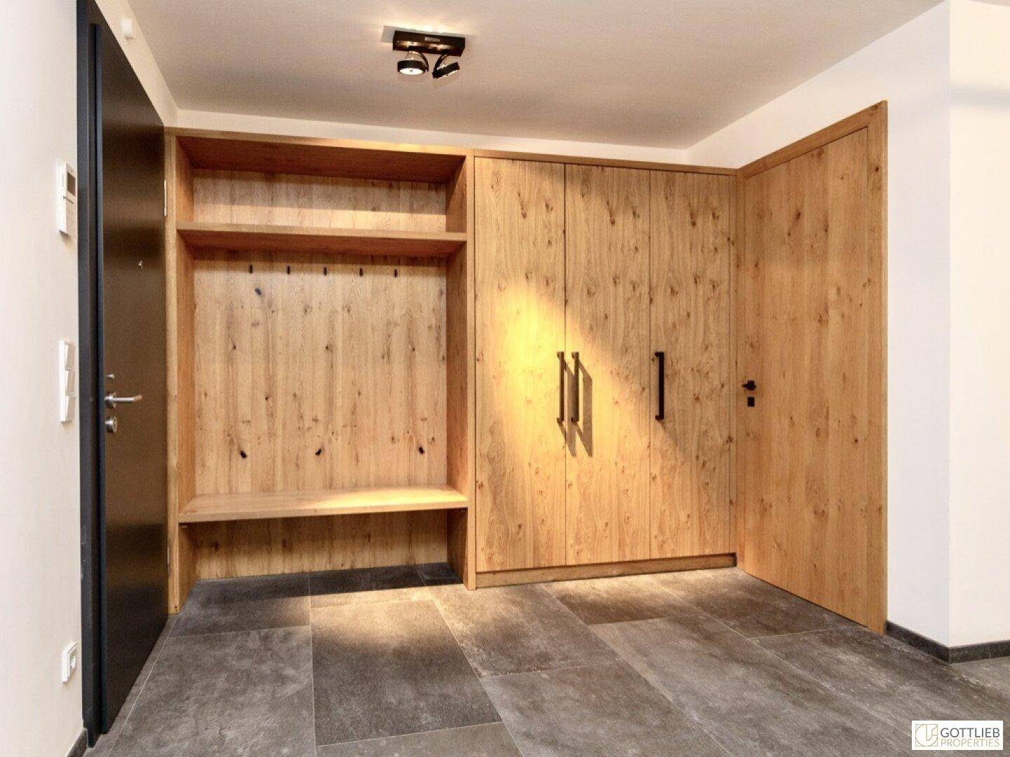 Eingangsbereich mit maßgefertigten Holzschränken und einer Sitzbank, ideal für Garderobe.