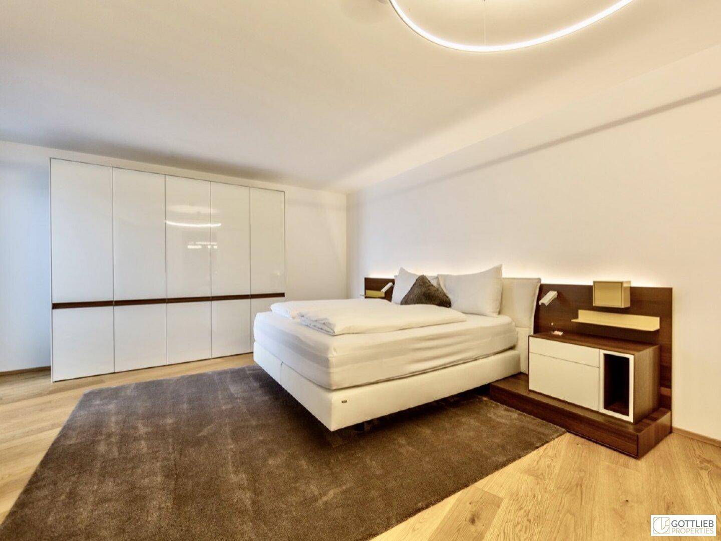 Modernes Schlafzimmer mit großem Doppelbett, integrierten Nachttischen und weißen Einbauschränken.