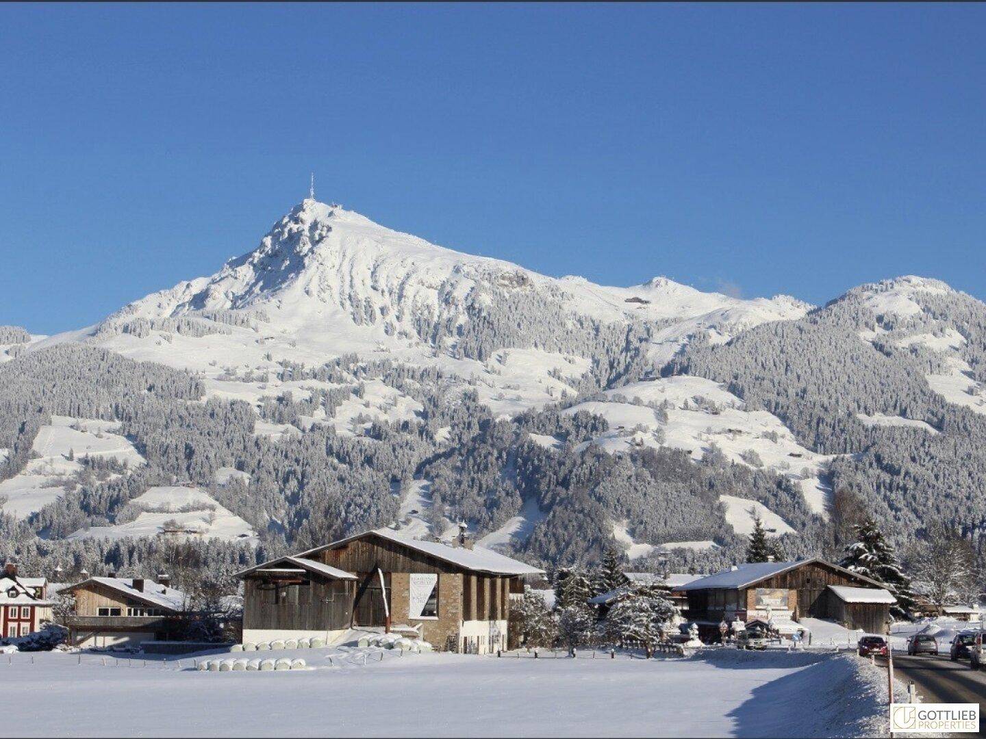 Winterlandschaft mit schneebedeckten Häusern und einem majestätischen Berg im Hintergrund.